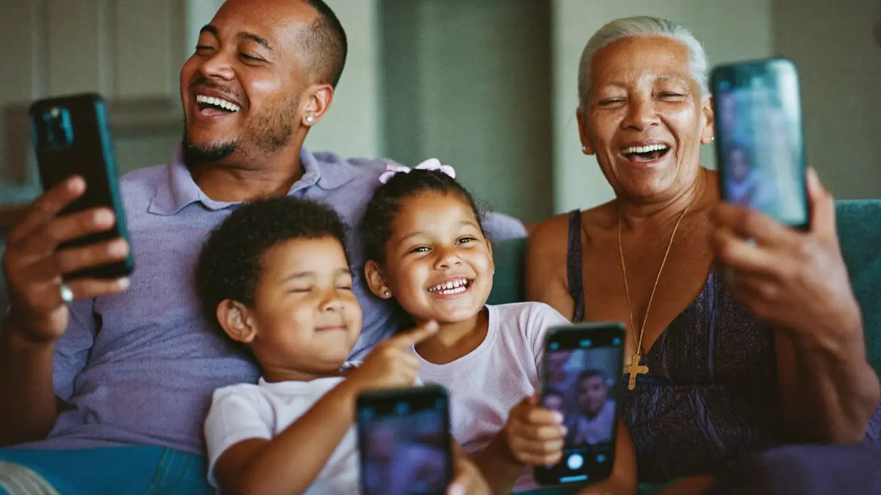 Família no sofá rindo enquanto assiste a um vídeo no celular