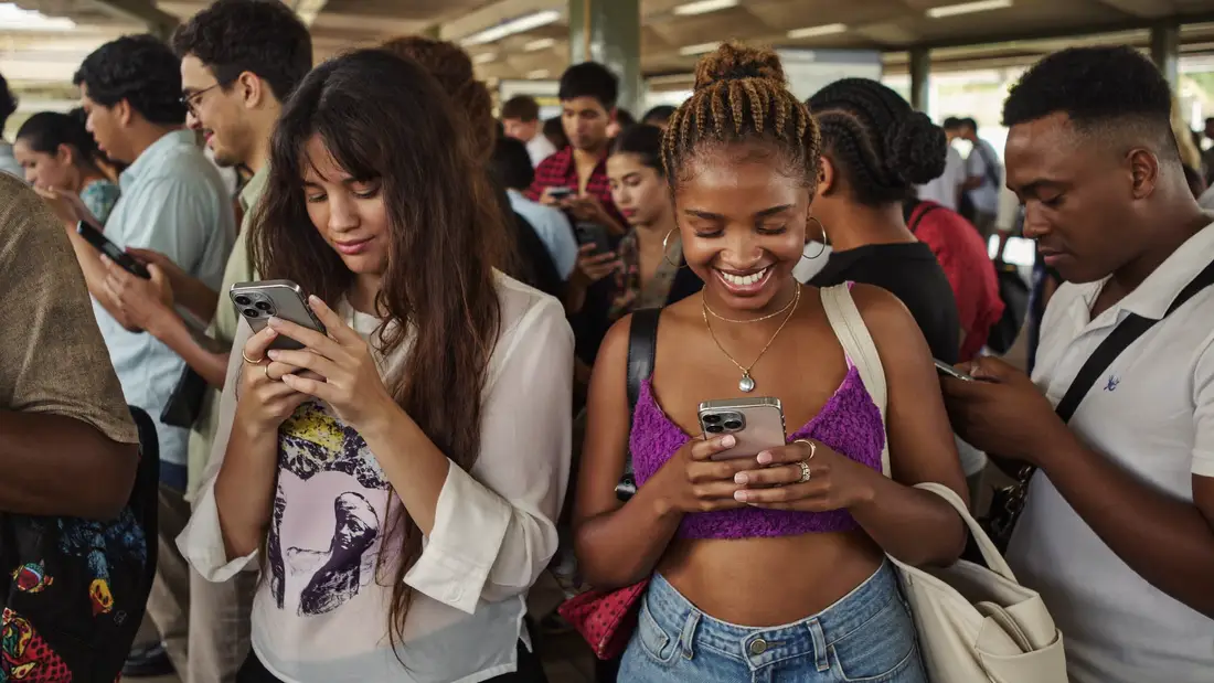 Pessoas no metrô olhando o celular, uma delas sorrindo para a tela
